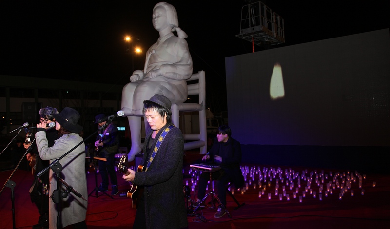 광주지역 락밴드 프롤로그가 촛불된 장식된 소녀상과 무대 앞에서 자작곡인 ‘소녀’를 부르며 시민문화제를 마무리하고 있다.