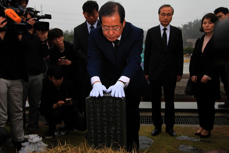 홍준표 자유한국당 대선 후보가 국립5·18민주묘지 분향 뒤 윤상원·박기순 열사 묘소를 찾아 참배하고 묘비에 고인 빗물을 닦아내고 있다.
