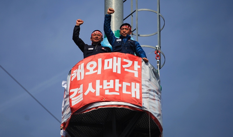 금호타이어 해외매각 철회 등을 촉구하며 광주 광산구 영광통 네거리 송신탑에서 고공농성을 벌이고 있는 조삼수 대표지회장(왼쪽)과 정송강 곡성지회장이 14일 오후 총파업 선포식에 참여한 조합원과 지역사회에 주먹을 불끈 쥐고 들어올리며 답하고 있다.