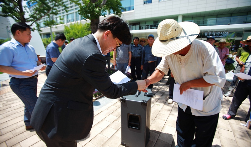 전농 광주시농민회는 12일 오후 광주광역시청 앞에서 이용섭 광주광역시장을 향해 농정개혁과 농업예산 확대를 강하게 촉구하고 있다. 오종원 광주시농민회장이 이 시장을 대신한 박정환 광주시 일자리경제국장에게 기자회견문을 전달하고 있다.