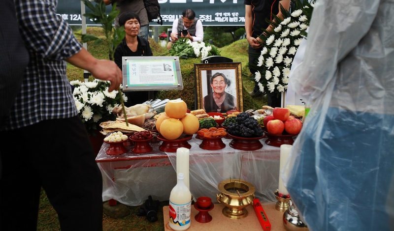 2주기 추모제를 마친 추모객들이 헌화하는 사이로 사진 속 고 백남기 농민이 미소를 짓고 있다.