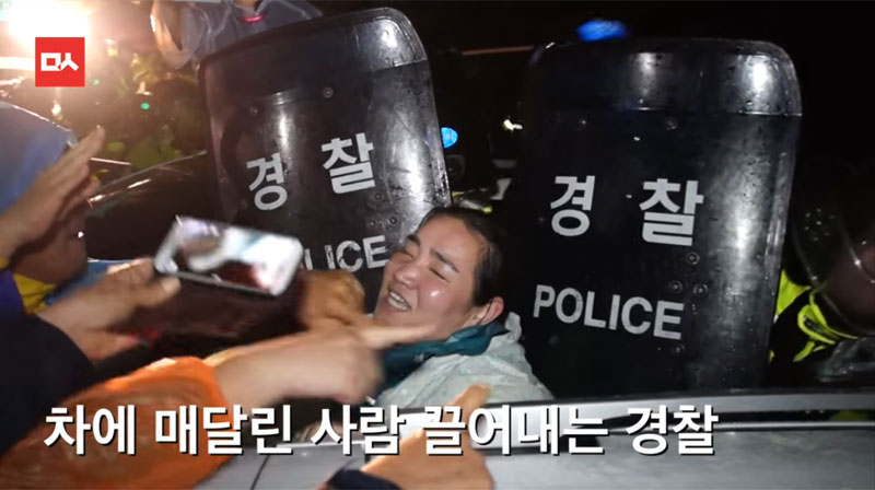 차에 매달려 저항하다 경찰에 진압당하는 원불교 여성 교무