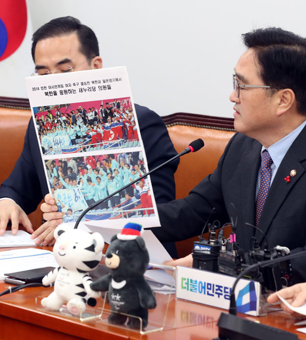 우원식 더불어민주당 원내대표가 지난달 23일 원내대책회의에서 자유한국당의 전신인 새누리당 의원들이 2014인천아시안게임 여자축구 결승전 북한과 일본 경기에서 북한을 응원하는 사진을 들어보이고 있다. 당시 새누리당 의원들은 ‘평화와 통일의 슛 골인!’이라는 현수막을 펼쳐든 채 북한팀을 응원했다.