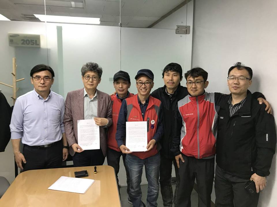 민주노총 민주일반연맹 서울일반노조 김형수 위원장(가운데)를 비롯한 조합원들과 탠디 정기수 대표이사(왼쪽 두번째)가 합의서를 작성하고 조인식을 하고 있는 모습.