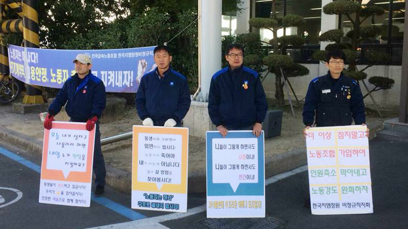 정규직 노동자들이 사내에서 연대를 호소하는 팻말을 들고 서 있다.