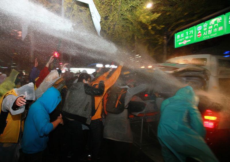 14일 오후 서울 종로 일대에서 경찰이 물대포를 맞고 실신한 민중총궐기 참가자가 응급차로 실려가는 동안에도 계속해서 물대포가 집중 발사되고 있다.