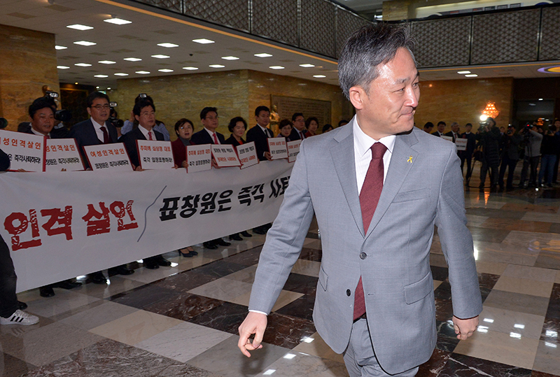 1일 오후 서울 여의도 국회 본회의장 앞에서 표창원 더불어민주당 의원 사퇴를 요구하는 새누리당 의원들 앞을 지나가고 있다.