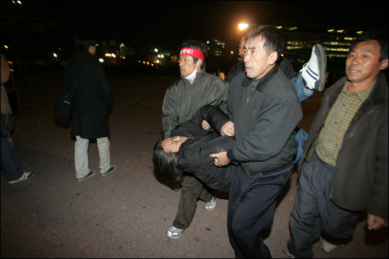 2005년 11월 15일 경찰에 폭행당해 쓰러진 고 전용철 농민을 다른 농민들이 발견해서 들고 공원을 빠져나가고 있다. ⓒ민중의소리 김철수 기자