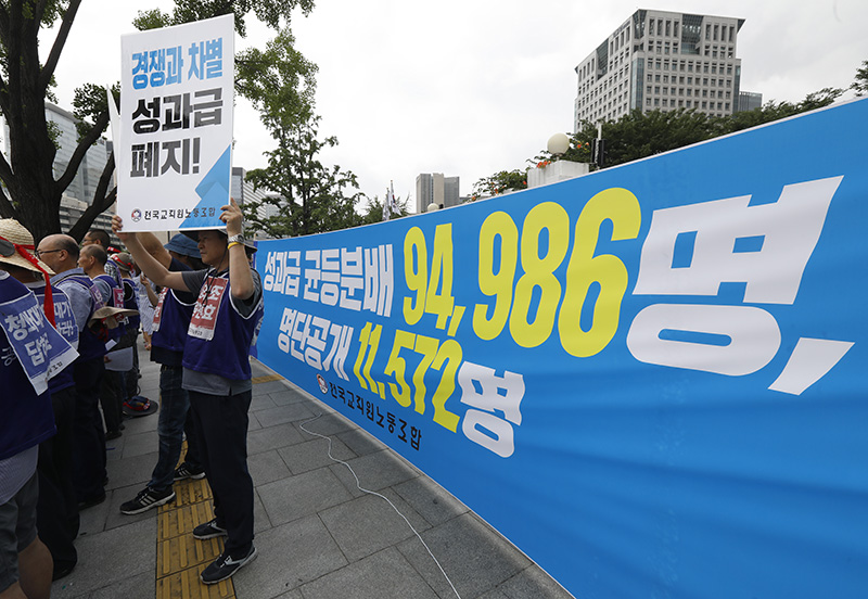 전국교직원노동조합(전교조) 조합원들이 12일 오전 서울 종로구 정부서울청사 앞에서 '2018년 성과급 균등분배 현황 및 실명 공개 발표 기자회견'을 열고 성과급 제도 폐지를 촉구하는 피켓을 들고 있다.