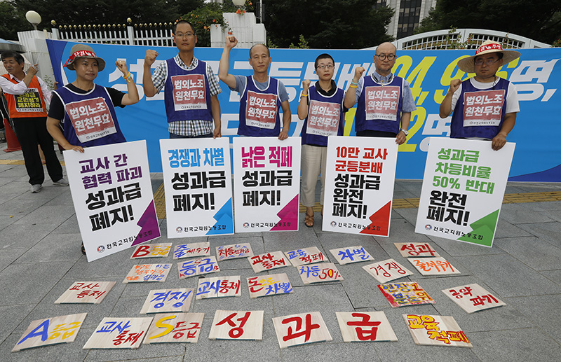 전국교직원노동조합(전교조) 조합원들이 12일 오전 서울 종로구 정부서울청사 앞에서 '2018년 성과급 균등분배 현황 및 실명 공개 발표 기자회견'을 열고 성과급 제도 폐지를 촉구하는 퍼포먼스를 하고 있다.