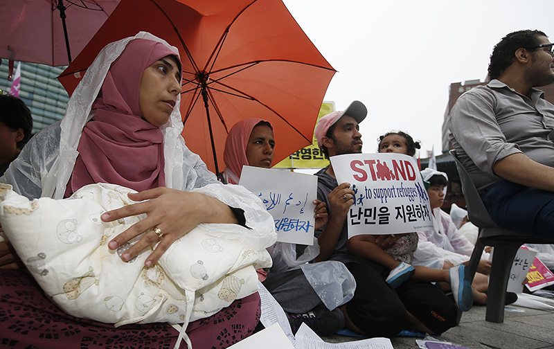 16일 오후 서울 보신각 앞에서 난민인권센터 주최로 열린 '난민과 함께하는 행동의 날' 집회에 참가한 난민 가족이 난민 지원을 촉구하며 피켓을 들고 있다.
