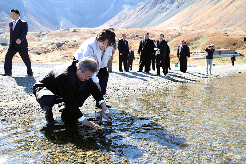문재인 대통령이 20일 오전 김정은 국무위원장과 백두산 천지를 산책하던 중 천지 물을 물병에 담고 있다.