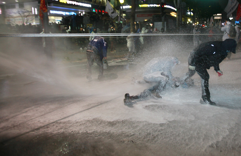 14일 오후 서울 종로구청입구 사거리에서 경찰이 물대포를 맞고 실신한 민중총궐기 참가자에게 물대포를 쏘고 있다.