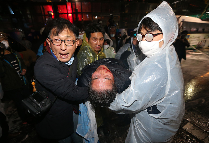 14일 오후 서울 종로구청입구 사거리에서 민중총궐기 참가자들이 경찰과 대치 중인 가운데 시민들이 경찰 물대포를 맞고 실신한 농민을 구급차로 옮기고 있다.