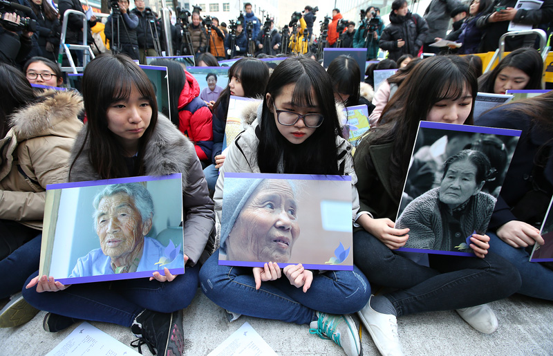30일 오후 서울 종로구 일본대사관 앞에서 한일 위안부 문제 협상 타결 이후 처음 열린 수요집회에서 참가자들이 세상을 떠난 위안부 피해 할머니들의 사진을 들고 있다.