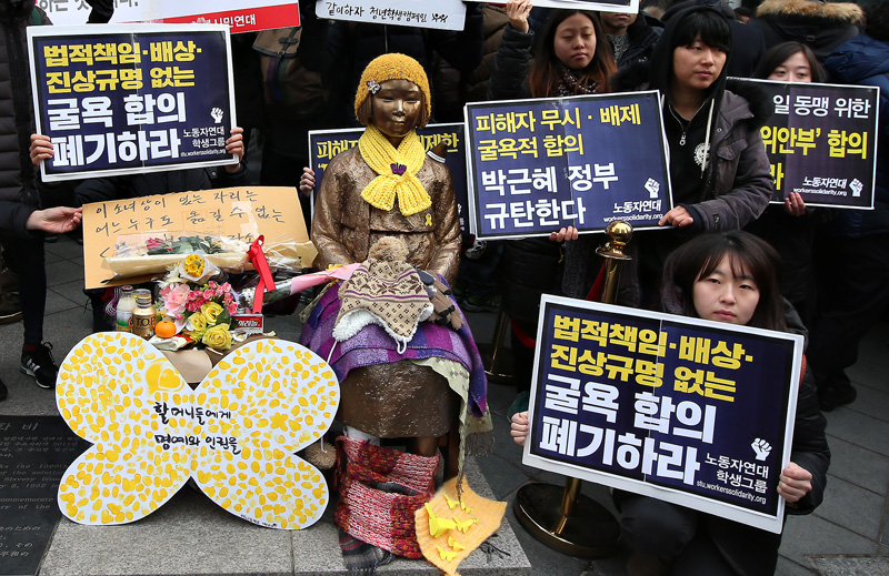 지난달 30일 오후 서울 종로구 일본대사관 앞에서 열린  일본군 위안부 문제 해결을 위한 제1211차 수요집회가 끝난 뒤 참가자들이 위안부 소녀상 옆에서  피켓을 들고 이전을 반대하고 있다.