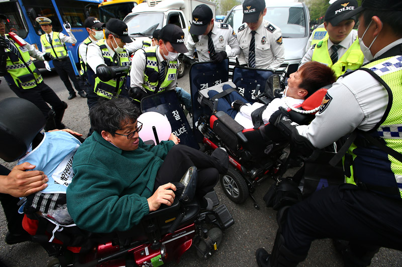 20일 오후 서울 광화문광장에서 열린 420 장애인차별철폐 투쟁결의대회를 마치고 행진에 나선 참가자들이 경찰에게 행진 보장을 요구하며 도로를 점거하고 있다.