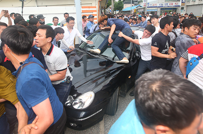 15일 오후 경북 성주군에서 주민들이 사드배치에 항의하며 한민구 국방부 장관이 탄 차에 뛰어오르고 있다.