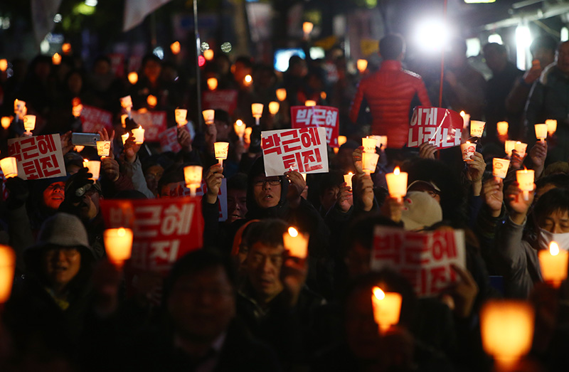 박근혜 대통령 하야 촉구 촛불집회에서 시민들이 촛불과 피켓을 들고 있다.