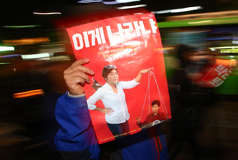 2일 오후 서울 종로구 종각 거리에서 박근혜 대통령 하야 촉구 촛불집회 참가자가 최순실과 박근혜 대통령을 풍자한 그림을 들고 행진하고 있다.