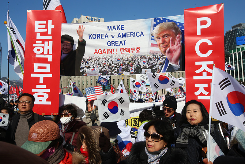 11일 오후 서울 중구 덕수궁 대한문 앞에서 열린 제12차 탄핵기각 총궐기 국민대회에서 참가자들이 박근혜 대통령과 트럼프 미 대통령의 사진을 들고 있다.