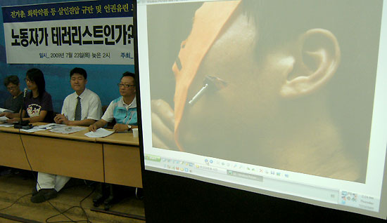 테이저건에 맞은 쌍용차 조합원의 사진을 보여주며 테이저건의 위험성을 설명하고있다.