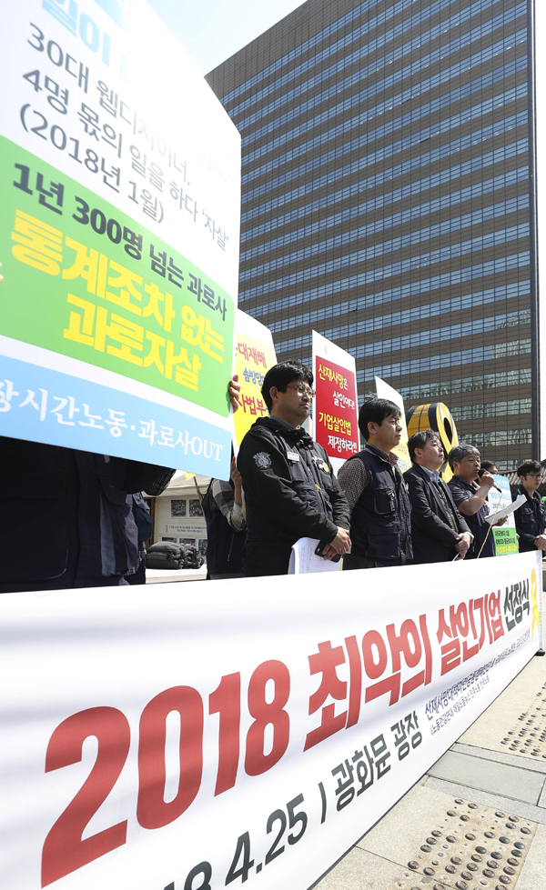 한 기자회견 참가자가 '통계조차 없는 과로 자살'을 비판하는 피켓을 들고 있다.