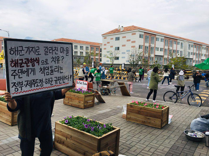 화단이 설치된 집회 장소에서 인간띠잇기 중인 제주 관함식 반대 주민