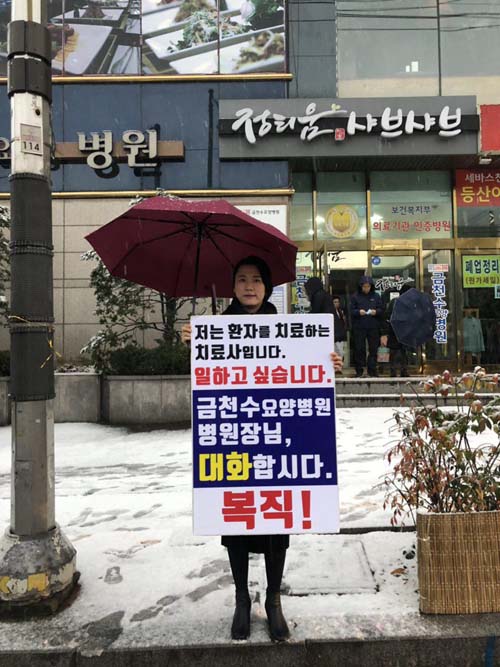 우시은 작업치료사가 눈을 맞으며 복직을 요구하는 1인 시위를 병원 앞에서 하고 있다.