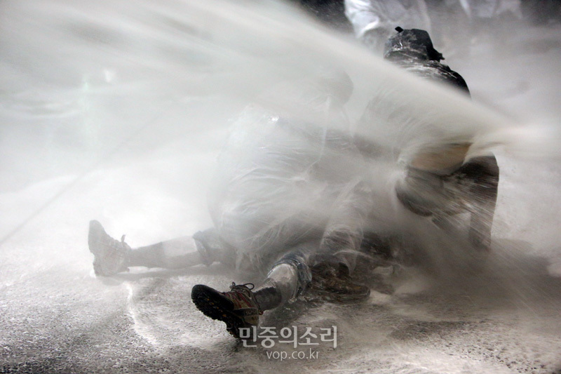 2015년 11월 14일 서울 종로구청입구 사거리에서 경찰이 물대포를 맞고 실신한 민중총궐기 참가자에게 물대포를 쏘고 있다.