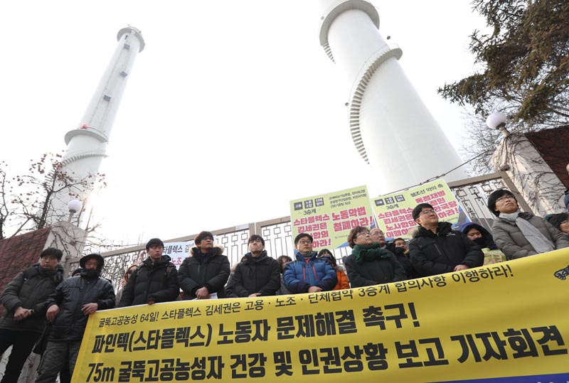 서울에너지공사 목동열병합발전소 75미터 굴뚝 고공농성장 앞에서 64일째 고공농성 중인 홍기탁 전 파인텍지회지회장과 박준호 사무장의 건강 및 인권상황 확인을 위해 만나고 온 조영선 국가인권위 사무총장, 홍종원 의사, 오춘상 삼대한의원 원장 등 금속노조 파인텍지회 관계자들이 파인텍 노동자 문제해결을 촉구하며 굴뚝고공농성자 건강 및 인권상황 보고 기자회견을 하고 있다.