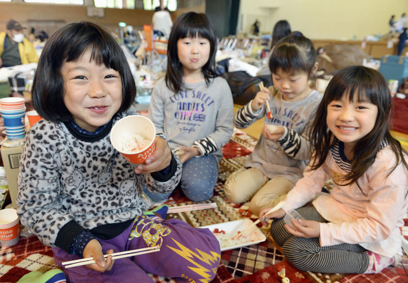 日本熊本県ミナミアソ待避所で子供たちが掛け声食糧を分けて食べて明るく笑っている. 2016.04.18