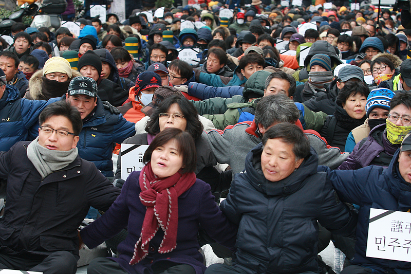 헌법재판소가 정부의 정당 해산심판 청구를 인용해 통합진보당 해산을 결정한 2014년 12월 19일 오후 서울 동작구 대방동 진보당사 앞에서 열린 진보당 해산 심판 규탄 대회에서 당원들이 서로의 어깨를 걸고 노래를 부르고 있다.