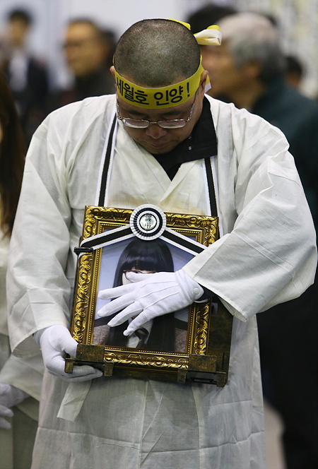 4일 경기도 안산시 화랑유원지에 마련된 세월호 참사 합동 분향소에서 유가족들이 세월호 특별법 시행령 폐기와 온전한 선체 인양을 촉구를 위한 도보 행진을 하기 전 영정 사진을 어루만지고 있다.