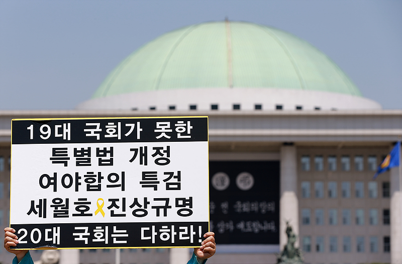 20일 서울 여의도 국회 앞에서 열린 19대 국회에서 세월호 특별법 개정 및 특검이 무산된 것과 관련한 기자회견에서 참가자가 20대 국회에서 세월호 특별법 개정과 특검을 촉구하는 손피켓을 들고 있다.