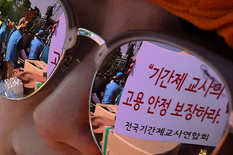 서울 여의도 문화마당에서 열린 전교조 결성 27주년 기념 전국교사대회가 열린 가운데 전국기간제교사연합회의 고용보장 손피켓이 참가자의 선글라스에 비치고 있다.