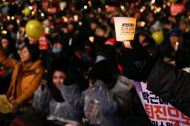 21일 서울 광화문광장에서 열린 박근혜 대통령 퇴진 촉구 13차 촛불집회에 참가한 시민이 헌재의 조기 퇴진 인용을 촉구하는 촛불을 들고 있다.