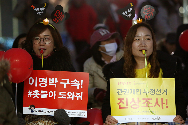 20일 오후 서울 광화문광장에서 열린 ‘이명박 전 대통령 수사 촉구 문화제’ 에 참가한 시민들이 이명박 전 대통령의 구속을 촉구하는 손피켓을 들고 호루라기를 불고 있다.