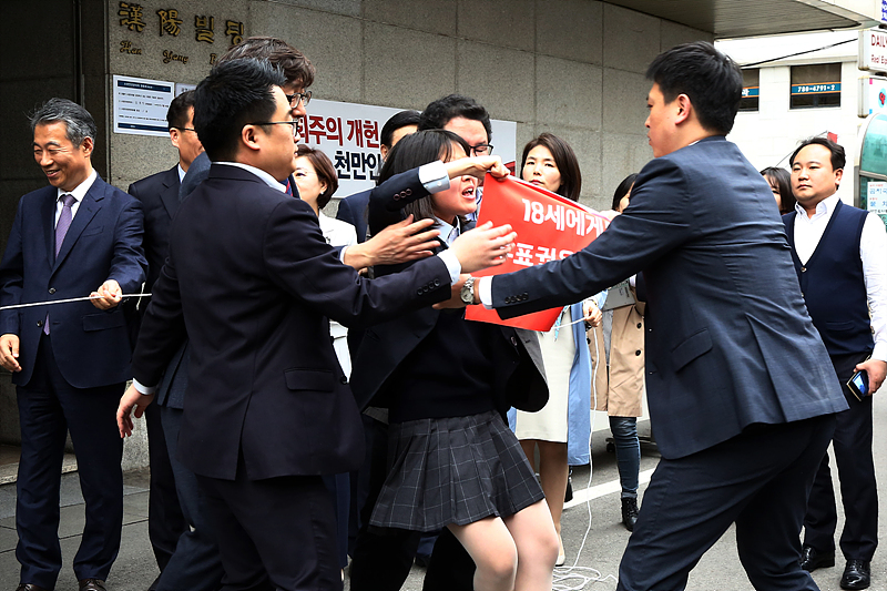 10일 오후 서울 여의도 자유한국당 중앙당사에서 열린 ‘사회주의 개헌·정책 저지 투쟁본부 현판 제막식’에서 당 당직자들이 선거연령 하향을 촉구하며 기습 피켓 시위를 하는 여고생을 가로막고 있다.