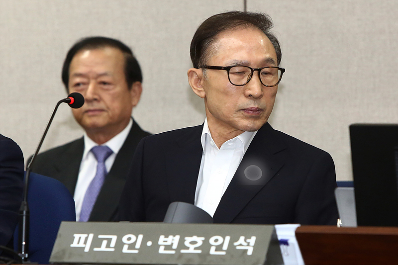 110억 원대 뇌물수수와 350억 원대 다스 횡령 등의 혐의로 구속된 이명박 전 대통령이 23일 오후 서울 서초구 서울중앙지방법원에서 열린 첫 공판에 출석해 피고인석에 앉아 있다.