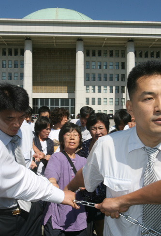 쇠사슬로 묶은 여성농민들을 끌어내는 국회 경위들