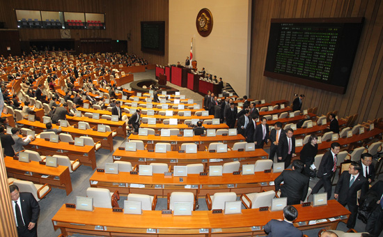 민주통합당 소속 의원들이 예산안 표결에 불참하기 위해 의석에서 일어나 본회의장 뒤로 이동하고 있다.