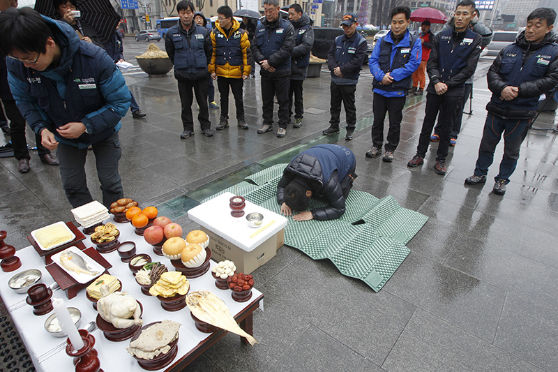 2015년 2월 16일 오전 서울 광화문 이순신동상 앞에서 열린 '설날 고향 못가는 체불 건설노동자 합동 차례 올리기 및 기자회견'에서 이용대 전국건설산업노동조합연맹 위원장이 건설노동자들과 차례를 지내고 있다