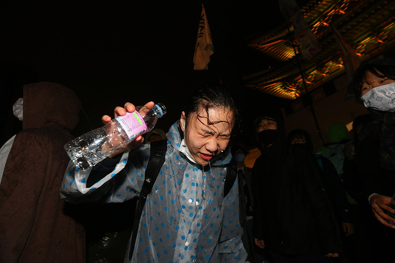 18일 오후 서울 경복궁 동십자각 앞에서 세월호 범국민대회 참가자가 광화문 누각 앞에서 농성 중인 세월호 유가족을 만나기 위해 경찰과 대치 중 경찰의 최루액을 맞아 물로 눈을 씻고 있다.