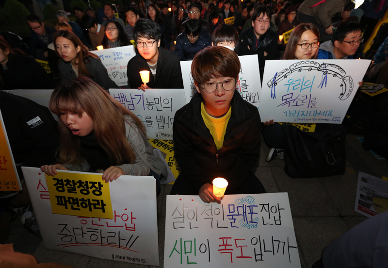 21일 오후 서울 태평로 파이낸스 빌딩 앞에서 열린 살인진압 경찰청장 파면 촉구, 백남기 농민 쾌유 기원 시민대회 참가자들이 손피켓과 촛불을 들고 있다.
