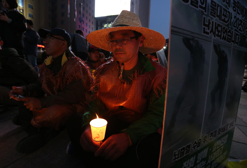 21일 오후 서울 태평로 파이낸스 빌딩 앞에서 열린 살인진압 경찰청장 파면 촉구, 백남기 농민 쾌유 기원 시민대회 참가자가 촛불을 들고 있다.