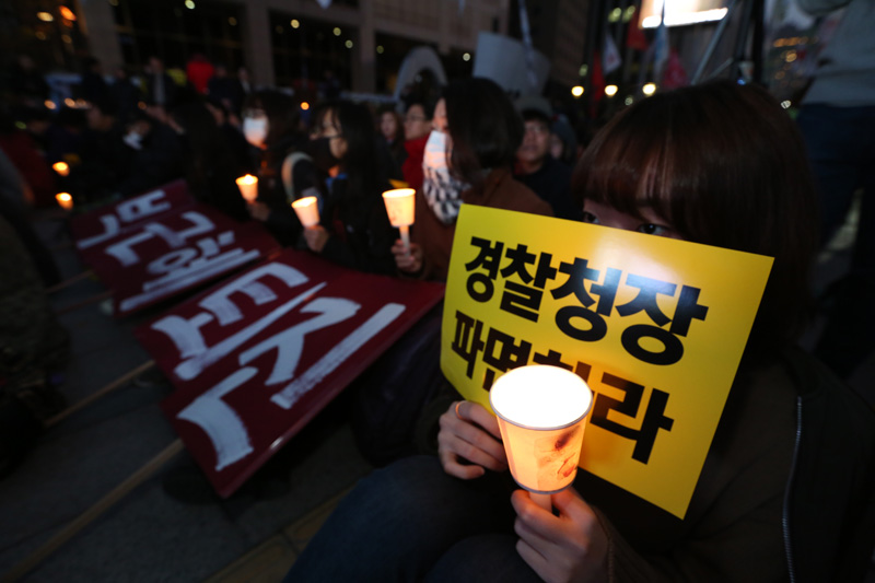 21일 오후 서울 태평로 파이낸스 빌딩 앞에서 열린 살인진압 경찰청장 파면 촉구, 백남기 농민 쾌유 기원 시민대회 참가자들이 손피켓과 촛불을 들고 구호를 외치고 있다.