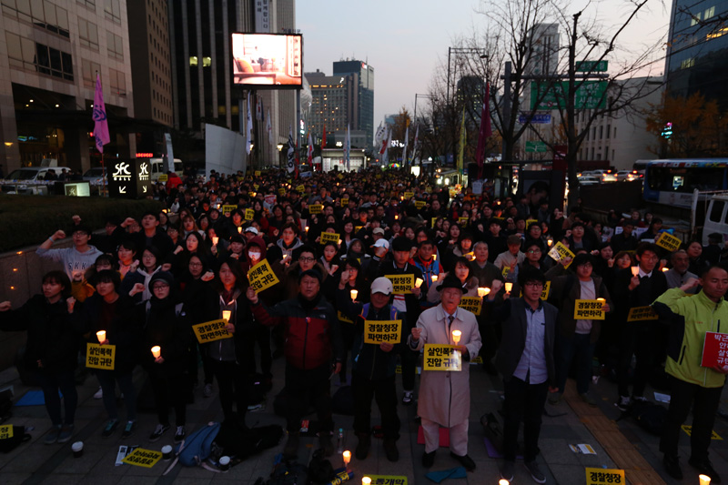 21일 오후 서울 태평로 파이낸스 빌딩 앞에서 열린 살인진압 경찰청장 파면 촉구, 백남기 농민 쾌유 기원 시민대회 참가자들이 손피켓과 촛불을 들고 구호를 외치고 있다.