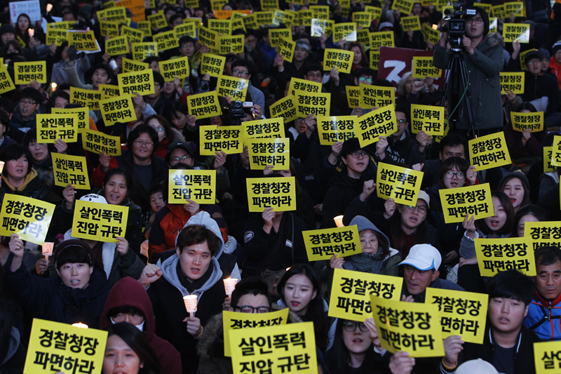 21일 오후 서울 태평로 파이낸스 빌딩 앞에서 열린 살인진압 경찰청장 파면 촉구, 백남기 농민 쾌유 기원 시민대회 참가자들이 손피켓과 촛불을 들고 구호를 외치고 있다.