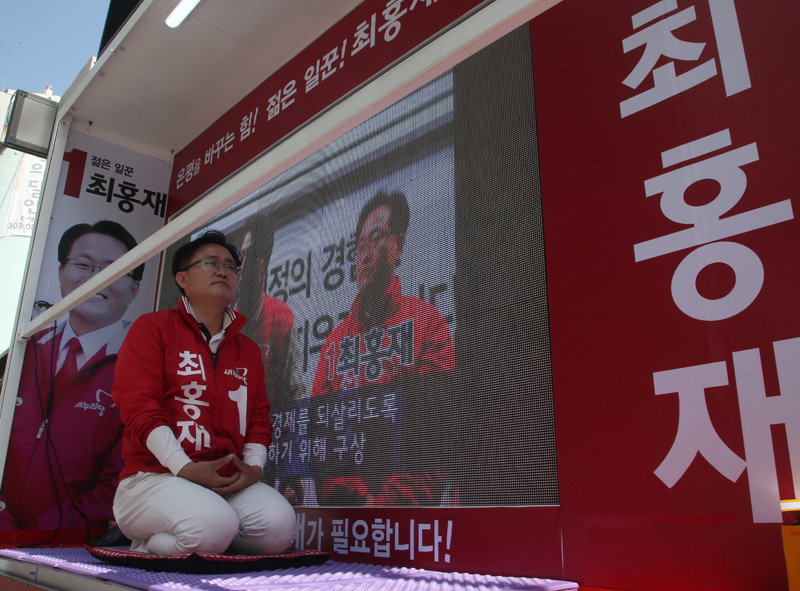 서울 은평갑에 출마한 새누리당 최홍재 후보가 11일 서울 은평구 수색동 주민센터 근처에서 유세차 위에 올라 무릎을 꿇고 시민들에게 지지를 호소하고 있다. 최 후보는 이 지역에 출마한 더불어민주당 박주민 후보가 더민주-국민의당 단일후보로 결정된 데 대해 반발, 12일 자정까지 '금식 유세'에 돌입했다.